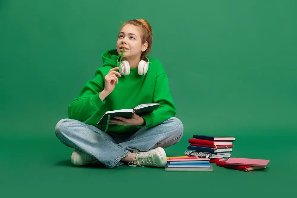 Étudiant réfléchissant à un sujet de mémoire, entouré de livres et d'idées sur un tableau.